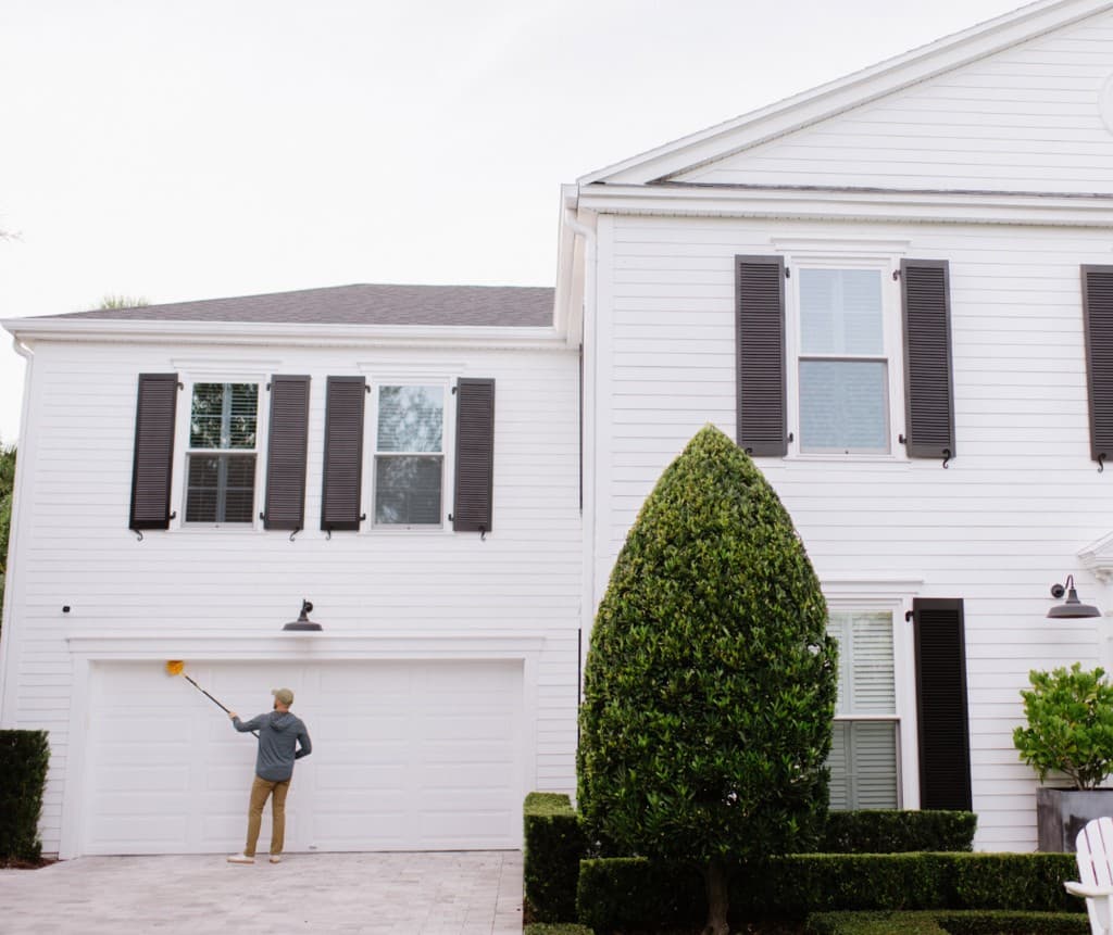 Panther Pest Control technician de-webbing the eaves and roofline of a home