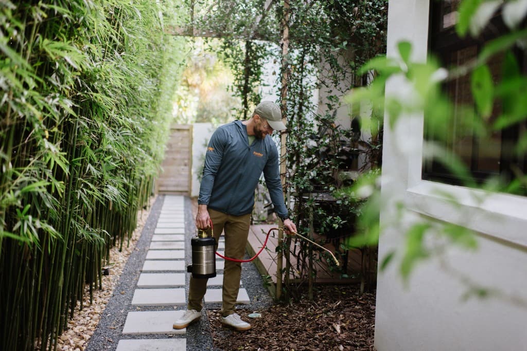 Panther Pest Control technician treating the perimeter of an Orlando home