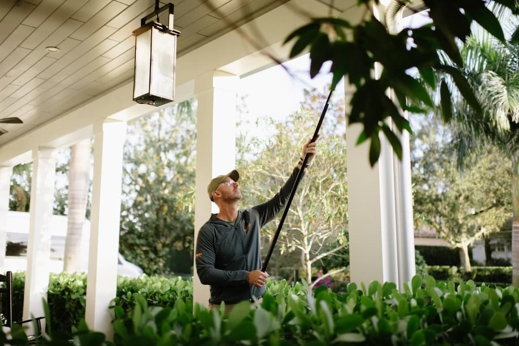 Panther Pest Control technician inspecting and treating a residential porch